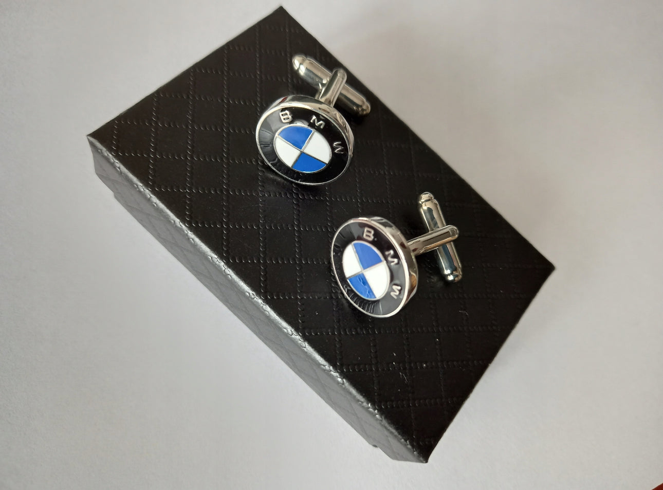 Elegante BMW mansjettknapper i polert sølvfarget metall. Størrelse: ca. 18 mm diameter. Farger: sølv, svart, blå og hvit. Laget av slitesterkt rustfritt stål med emaljedetaljer. Perfekt til dress og skjorte – ideell gave til bilentusiaster og stilbevisste menn.