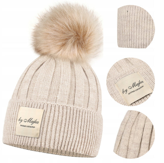 Stilig og varm dame lue med pompom i beige farge, laget av 100% akryl med fleecefôr i 100% polyester for ekstra varme. One size – elastisk og tilpasser seg hodets form. Perfekt for høst og vinter, gir både stil og komfort.