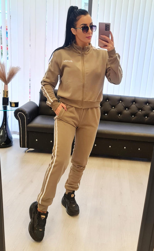 Stilfull joggedress uten hette i khaki med sporty striper. To-delt sett med glidelåslukking og elastisk midje for maksimal komfort. Tilgjengelig i størrelsene S/M, M/L, L/XL og XL/2XL. Mykt og behagelig stoff, perfekt til både hverdagsbruk og fritid.