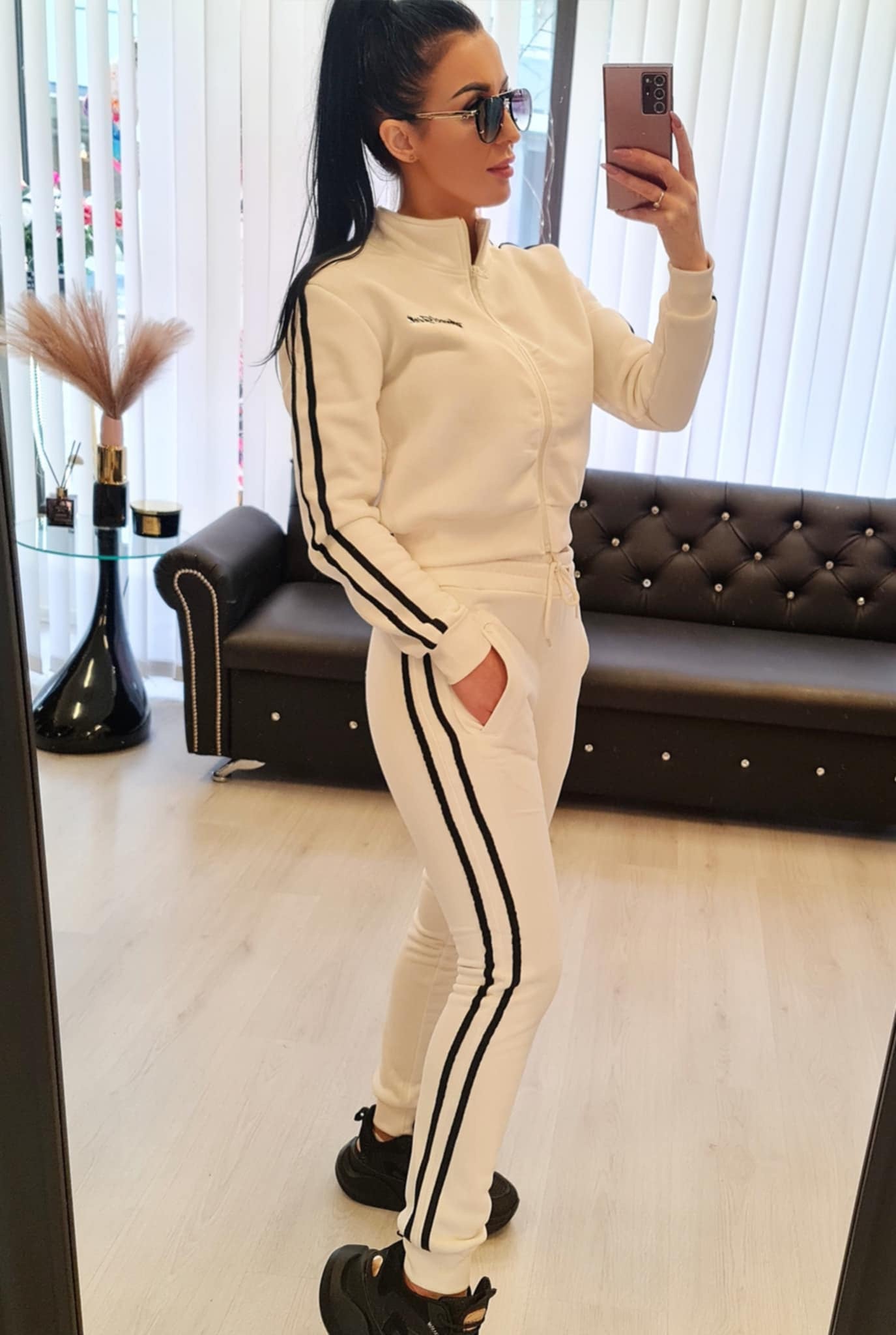 Dame joggedress i fargen hvit, laget av myk bomullsblanding. Sporty design med striper langs ermene og buksene. Tilgjengelig i størrelsene S/M, M/L, L/XL og XL/2XL. Perfekt for fritid, trening og hverdagsbruk.