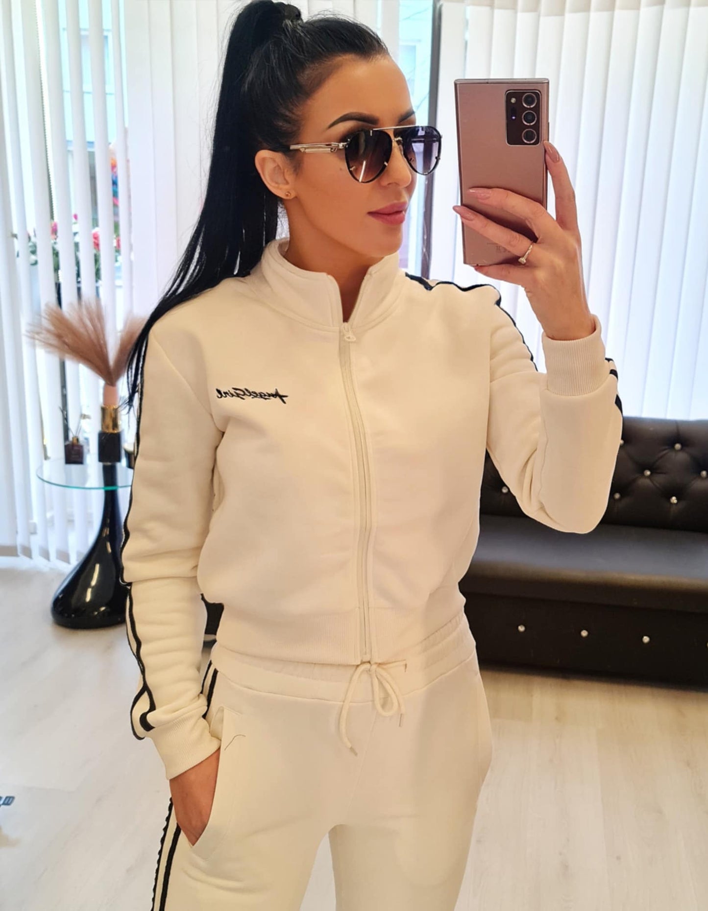 Dame joggedress i fargen hvit, laget av myk bomullsblanding. Sporty design med striper langs ermene og buksene. Tilgjengelig i størrelsene S/M, M/L, L/XL og XL/2XL. Perfekt for fritid, trening og hverdagsbruk.