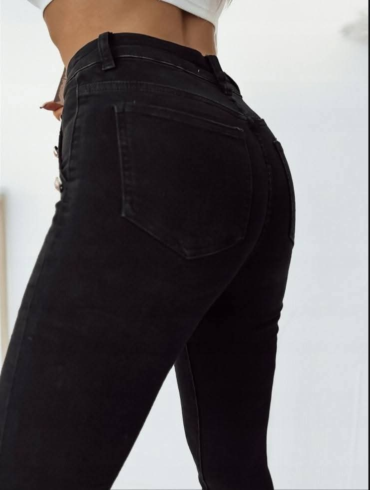 Høyt liv skinny jeans dame – sort farge, tilgjengelig i størrelser 26-32. Elastisk slim fit-passform med stretch for komfort og perfekt passform. Stilfulle knappedetaljer foran. Ideell til både hverdagsbruk og fest.